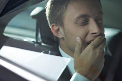 Young businessman yawning in car